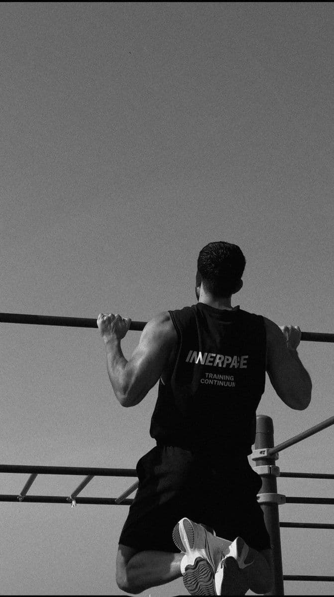 An athlete pulling up to a bar outdoors, shot from below against an open sky