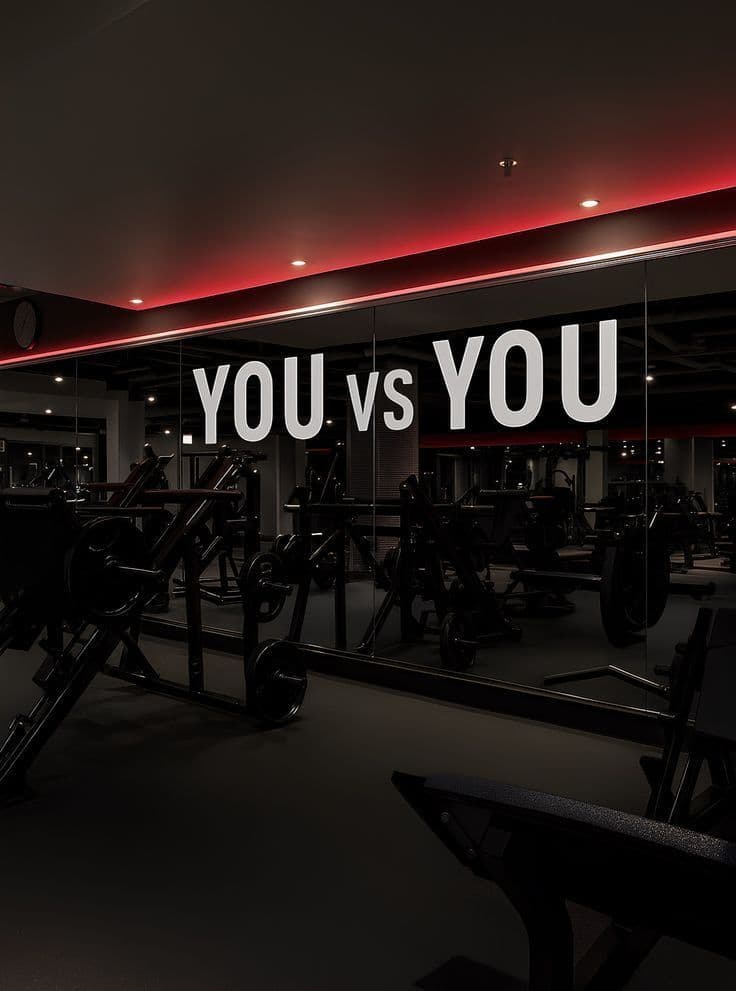 An empty, dimly lit gym floor with racked plates and benches